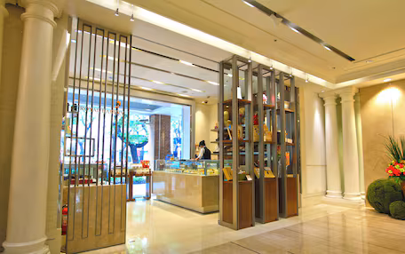 A modern hotel lobby with a bakery counter, marble flooring, and classical columns.