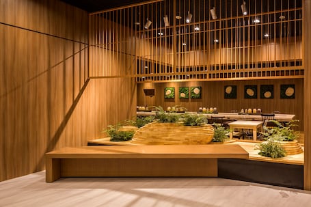 A hotel entrance with a brick facade, outdoor seating area, and potted plants.