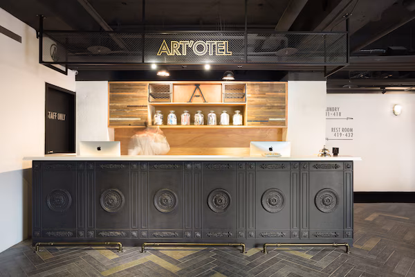A reception desk with a sign reading "ART'OTEL," a wooden shelf with jars, and a "TAFF ONLY" door.