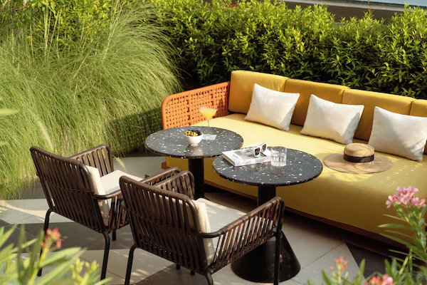 A hotel entrance with a brick facade, outdoor seating area, and potted plants.