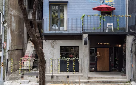 A building with a blue facade, graffiti art, and a red umbrella outside a shop named "i'm inn taipei".