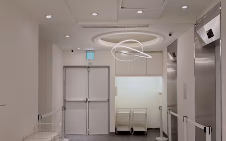 A modern hotel lobby with a grey carpet, a white sofa, a round table, and a reception desk.
