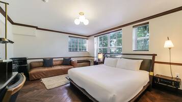 A hotel room with a large bed, a sofa, a desk, and a lamp.