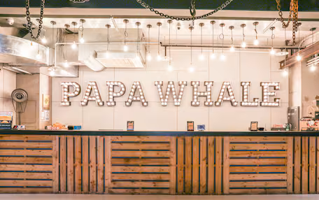 A reception desk with a sign reading "PAPA WHALE" and a wooden slatted design.