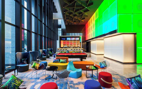 A modern lounge area with a pool table, comfortable seating, and large windows offering city views.