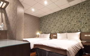 A hotel room with two beds, a desk, and a patterned wall.