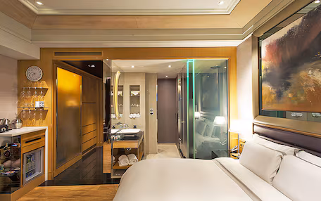 A hotel room with a bed, a bathroom, and a minibar.