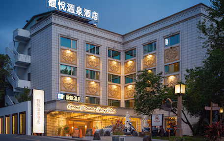 A hotel with a modern facade, large windows, and a sign indicating it is a Grand Pleasure Spring Hotel.