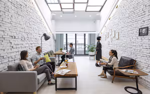 A modern office space with white brick walls, a wooden table, and a sofa.