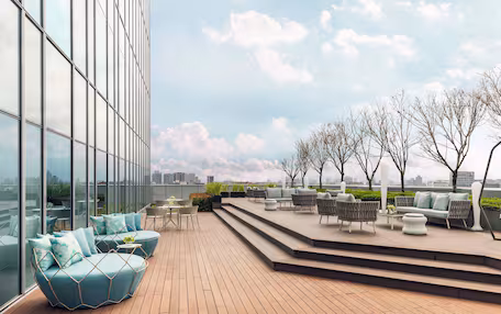 A rooftop terrace with seating areas, a view of the cityscape, and a clear sky.