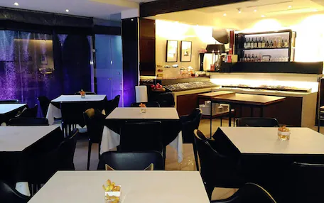 A restaurant with tables and chairs, a bar area with bottles, and a piano.