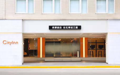 A hotel entrance with a sign indicating it's a new hotel at a train station.