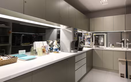 A modern kitchen with built-in appliances, a white countertop, and grey cabinetry.