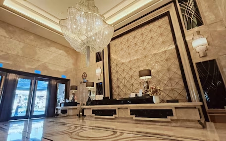 A lobby with a chandelier, reception desk, and a geometric patterned wall.