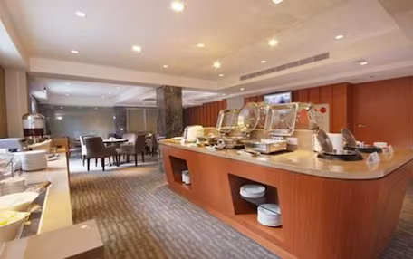 A buffet area with a marble countertop, multiple serving stations, and a seating area with chairs and tables.