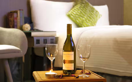 A bottle of Santa Helena Chardonnay 2011 on a bedside table with two empty wine glasses and a lit candle.