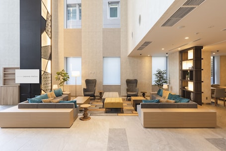 A hotel entrance with a brick facade, outdoor seating area, and potted plants.