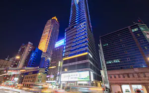 A high-rise building with illuminated signage, including a prominent Panasonic sign.