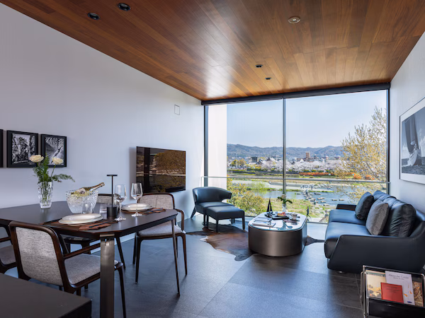 A modern living room with a dining area, large windows, and a view of a cityscape.